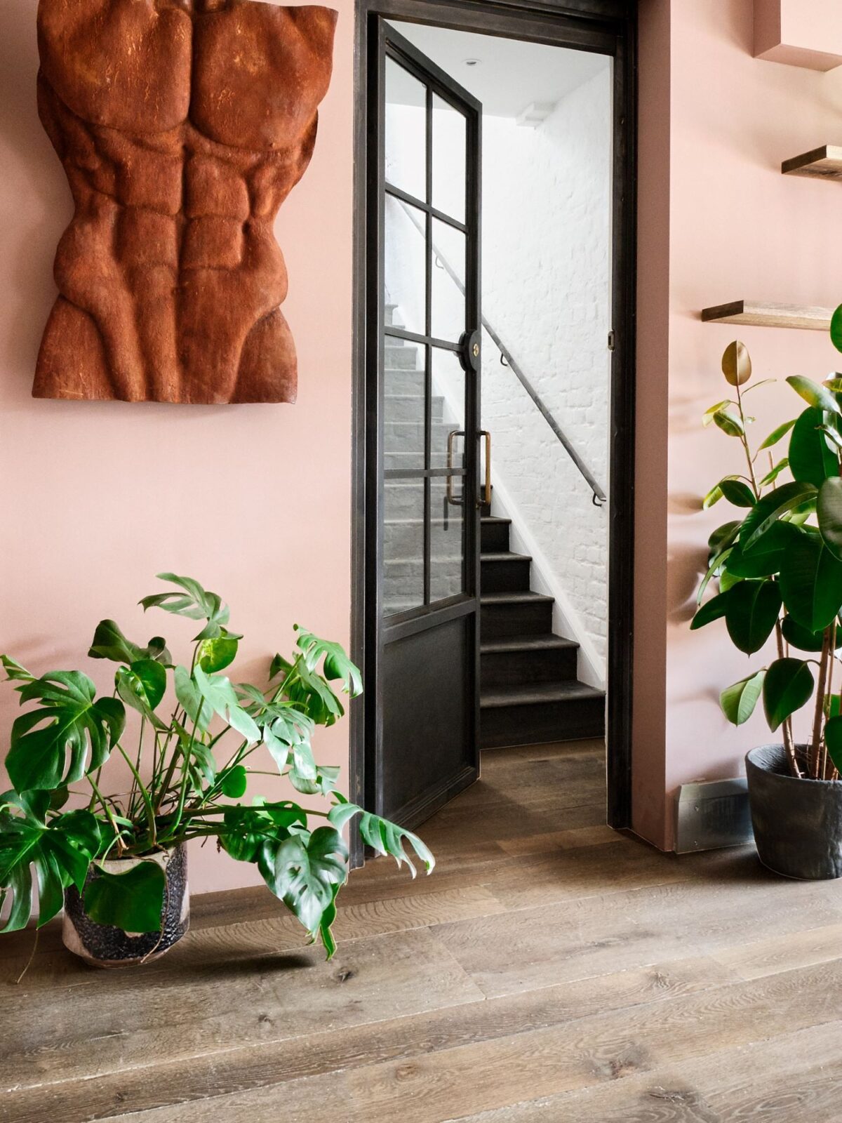 Oak Landmark Compton wide board engineered flooring in rustic distressed finish with steel doors plants and bronze sculpture