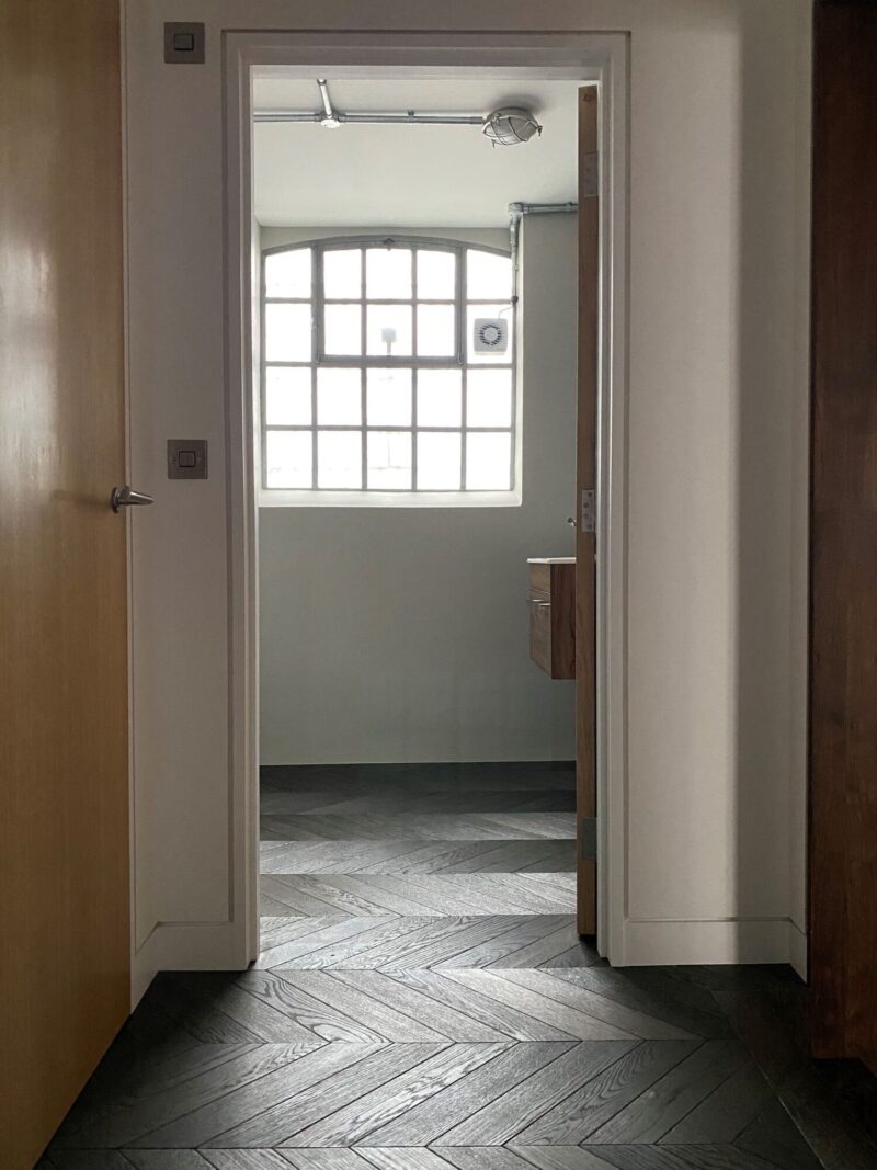Black engineered chevron floor County Rutland in hallway and bathroom