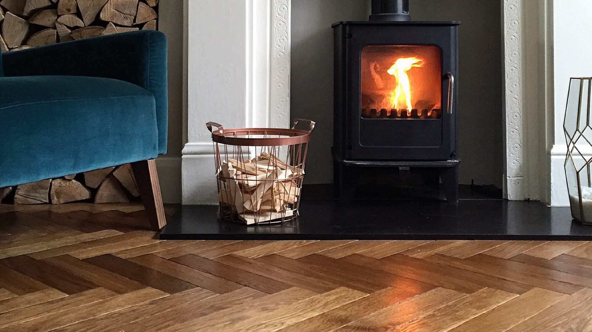 Landmark Dalton herringbone floor with blue velvet chair and wood burner