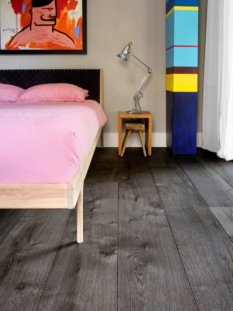 Magma mayon dark textured oak engineered floor in bedroom with colourful art and anglepoise lamp
